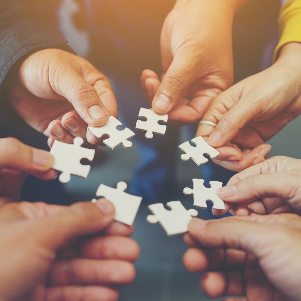 teamwork showing group of hands holding a piece of a puzzle that belongs together